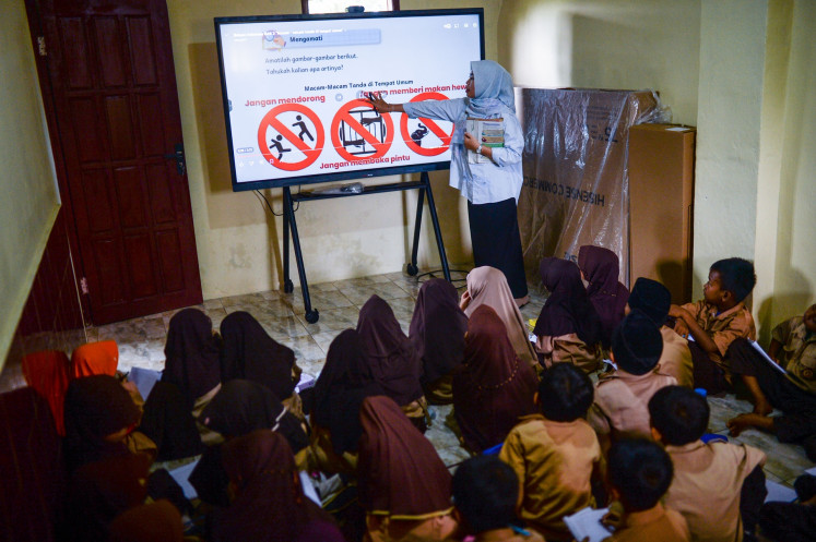 A teacher uses an interactive smart screen to teach students on Oct. 3 at SDN Panunggulan 2 state elementary school in Serang regency, Banten.