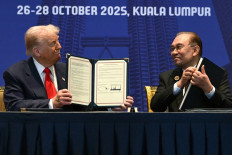 US President Donald Trump (left) and Malaysia's Prime Minister Anwar Ibrahim (right) hold signed documents during a bilateral meeting on the sidelines of the 47th Association of Southeast Asian Nations (ASEAN) Summit in Kuala Lumpur on October 26, 2025. 