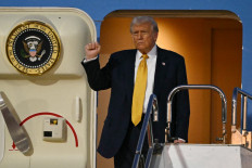 US President Donald Trump gestures as he prepares to alight from Air Force One upon arrival at Haneda Airport in Tokyo on October 27, 2025. Donald Trump arrived in Japan on October 27, the next leg of an Asia tour that could see the US president and China's Xi Jinping end the bruising trade war between the world's largest economies.