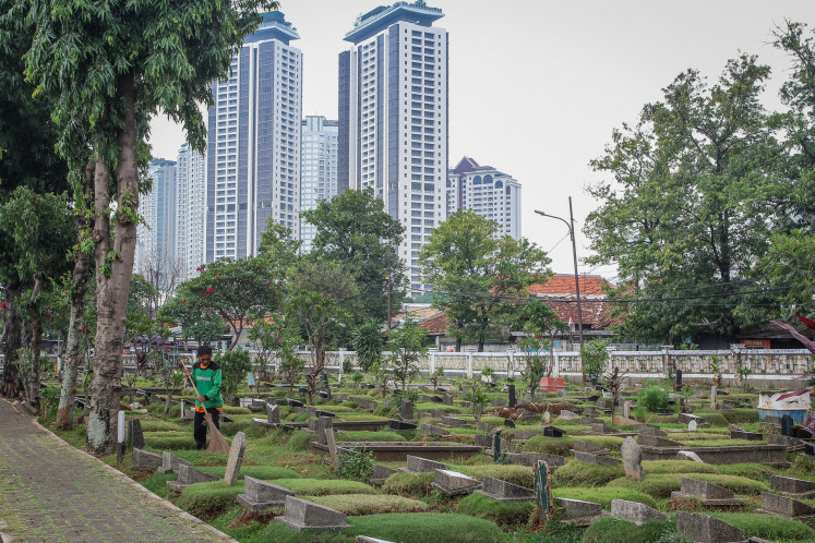 A groundskeeper tidies a grave on Oct. 21, 2025, at the South Grogol Public Cemetery (TPU) in South Jakarta. Nine TPU in the municipality are at full capacity and have started turning to stacked burials to accommodate demand.