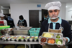 A worker at the Surabaya Police’s nutrition fulfillment service unit (SPPG) shows a tray of food to be distributed under the free nutritious meal program on Oct. 29, 2025, in the East Java capital.