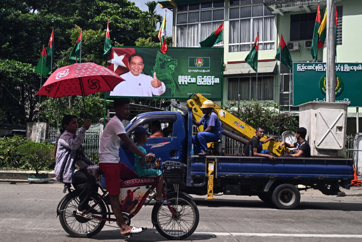 People drive past an election campaign billboard of Myanmar's chairman of the army-backed ruling Union Solidarity and Development Party (USDP) Khin Yi on Oct. 27 ahead of the start of the election campaign in Yangon. Junta chief Min Aung Hlaing has billed the December 28 polls as a step toward reconciliation in the civil war unleashed by his 2021 coup.