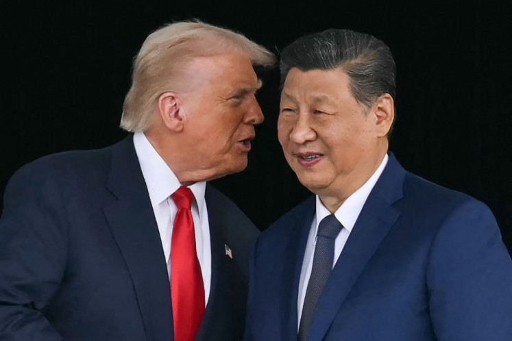 US President Donald Trump (left) talks to China's President Xi Jinping as they shake hands after their talks at the Gimhae Air Base, located next to the Gimhae International Airport in Busan on October 30, 2025. US President Donald Trump and China's leader Xi Jinping opened on October 30 their first face-to-face meeting in six years, seeking a truce to end a trade war that has roiled the world economy. 