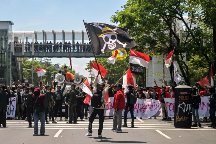 A demonstrator waves a pirate flag from Japanese anime One Piece on Aug. 30, an internet trend used to criticize government policies, during a protest in in Surabaya following the death of an ojol (online motorcycle transportation) driver who was run over by a police tactical vehicle on Aug. 28 during earlier rallies against low wages and financial perks for lawmakers in Jakarta.