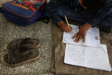 A Palestinian boy takes notes on his notebook at a school in the Nuseirat refugee camp, in the central Gaza Strip, on Oct. 26, 2025, after a United States-brokered ceasefire came into effect earlier in the month. With Gaza's education system shattered by two years of gruelling war, UNICEF's regional director said on Oct. 23 that he feared for a “lost generation“ of children wandering ruined streets with nothing to do.