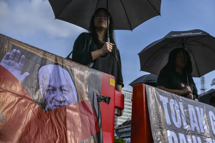 Activists of the Thursdays (kamisan) silent protest stand with banners reading 'Reject the Hero Title for Suharto' as they protest to demand justice for activists who were killed in the 1998 Semanggi tragedy in front of the Presidential Palace in Jakarta on July 3, 2025. In the late 1990s, deadly riots preceded Indonesian dictator Suharto's fall, but the government says the racialy-motivated bloodbaths that mostly targeted ethnically Chinese Indonesians will be skipped in a forthcoming revision of its official history books, slated to be launched in December.