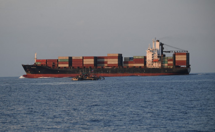In this photo taken on May 16, 2024, a cargo ship sails past a Philippine fishing boat with volunteers from a civilian-led mission Atin Ito (It's Ours) Coalition onboard in South China Sea, as they sail back to port. 