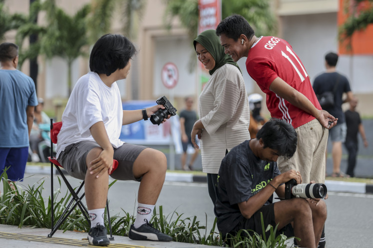 A street photographer ('left') shows his work to passersby during a Car Free Day event in Ternate, North Maluku on Sunday. 