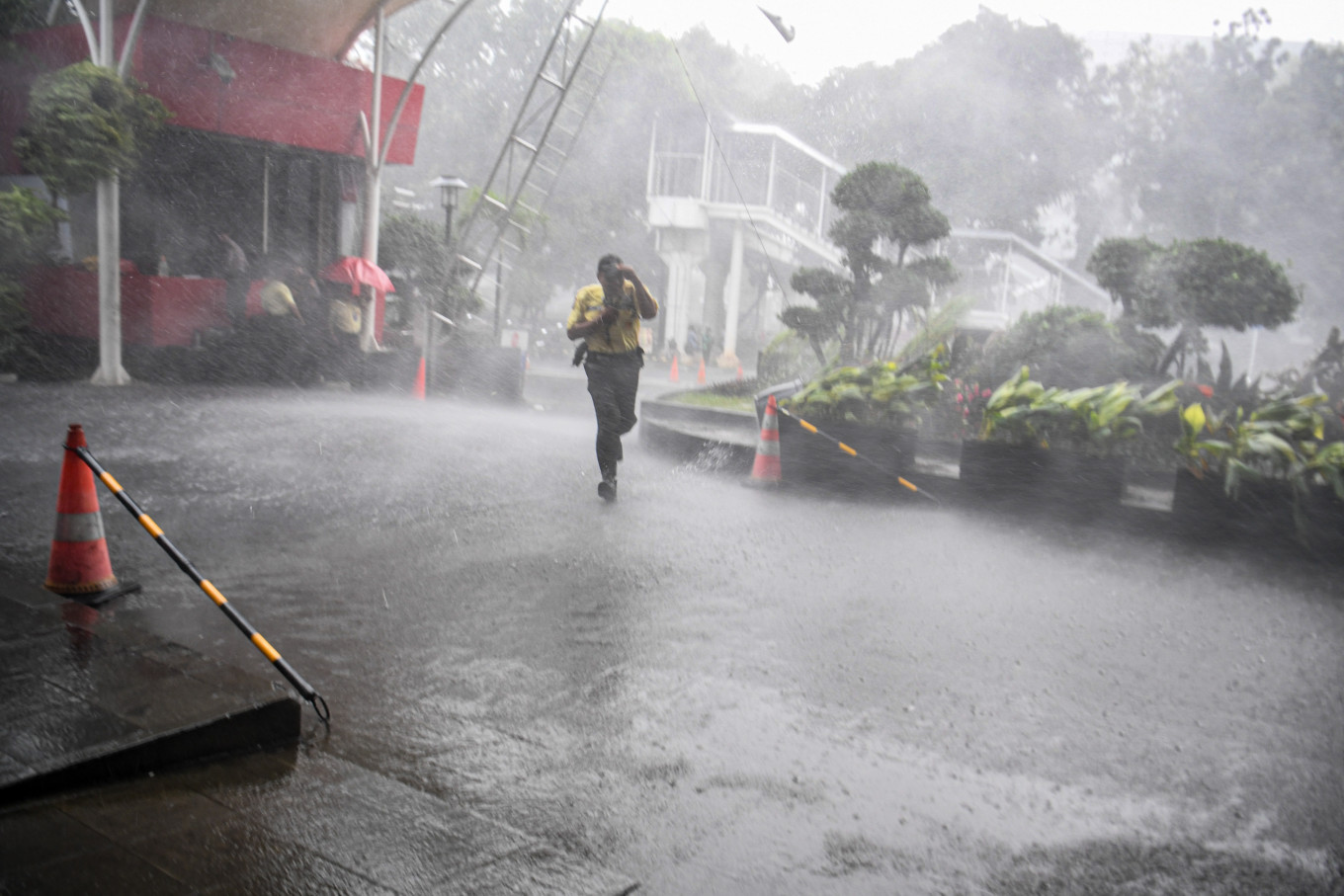 A security guard runs through a heavy rain shower on Nov. 3 at the Corruption Eradication Commission (KPK) headquarters in Jakarta.
