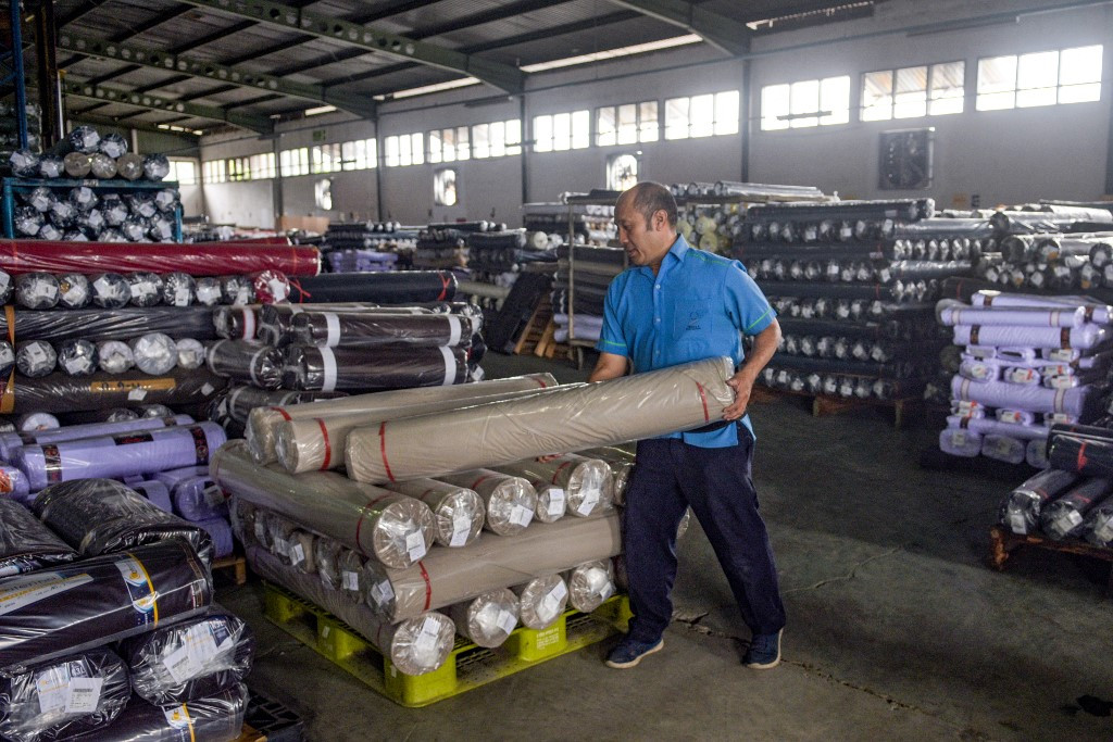 A worker stacks rolls of fabric ready for export on April 15 at the Trisula Textile Industries factory in Cimahi, West Java.