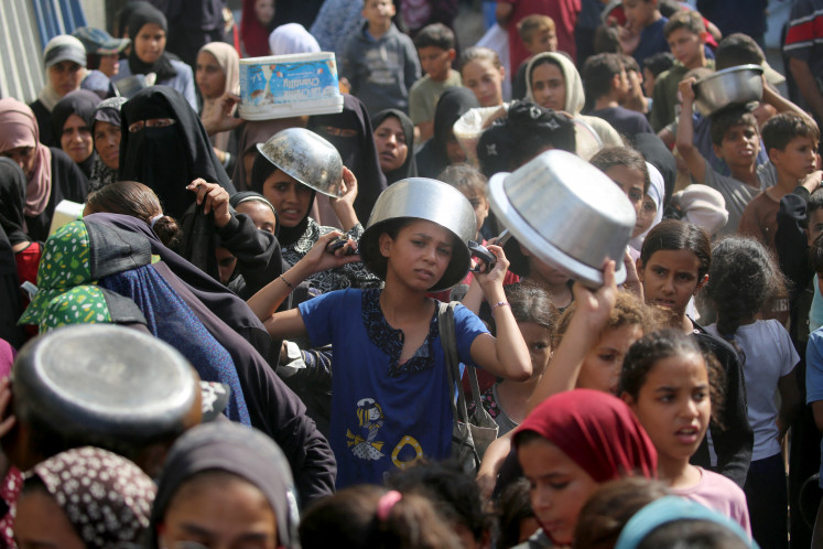 The plight of children: A young displaced Palestinian boy waits with his pot to receive a portion of food on Sunday, November 02, 2025, at a shelter where families have been living, in Nuseirat in the central of Gaza Strip.