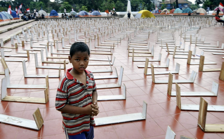A boy walks past a mock cemetery is seen as a symbol Soeharto's regime victims as activists hold a people tribunal to judge Soeharto's cases before he stept down in 1998 in Jakarta on February 12, 2008.  