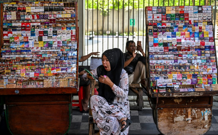 A cigarette vendor waits for customers on Oct. 10, 2024, at her stall along a road in Surabaya, East Java.