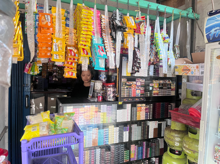 Warung madura shopkeeper Dia is seen behind the counter on Nov. 5. The small shop is located two buildings away from an Alfamart outlet in Palmerah, West Jakarta.
