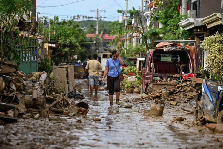 A woman walks along a muddy street on Nov. 6, in Liloan, Cebu province, after Typhoon Kalmaegi left a trail of devastation across the central Philippines.