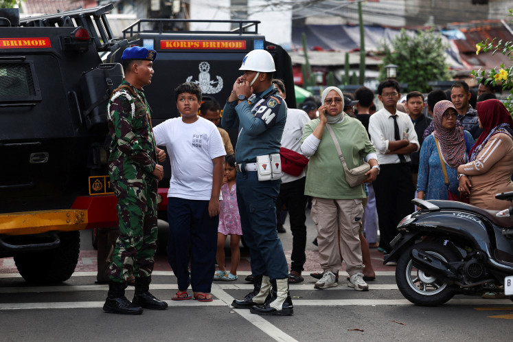 Military personnel guard as residents gather near the area after an explosion occurred at state high school SMAN 72 complex in Kelapa Gading, North Jakarta, November 7, 2025. 
