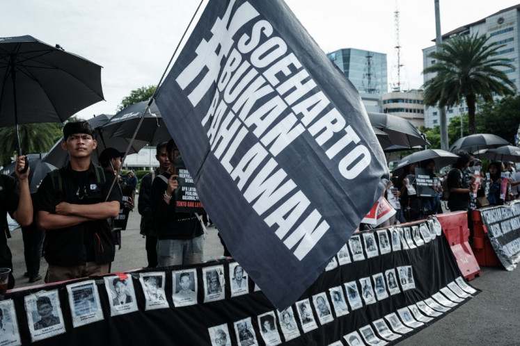 A member of a civil society group ('left') holds a banner that reads “Suharto is not a hero“ during the 'Kamisan' (Thursday) rally on Nov. 6, 2025, opposing the government's plan to give former president Soeharto the title of national hero, near the presidential palace in Jakarta. Suharto, who died in 2008 aged 86, ruled Indonesia with an iron fist for more than three decades after seizing power in 1967.