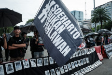 A member of a civil society group ('left') holds a banner that reads “Suharto is not a hero“ during the 'Kamisan' (Thursday) rally on Nov. 6, 2025, opposing the government's plan to give former president Soeharto the title of national hero, near the presidential palace in Jakarta. Suharto, who died in 2008 aged 86, ruled Indonesia with an iron fist for more than three decades after seizing power in 1967.