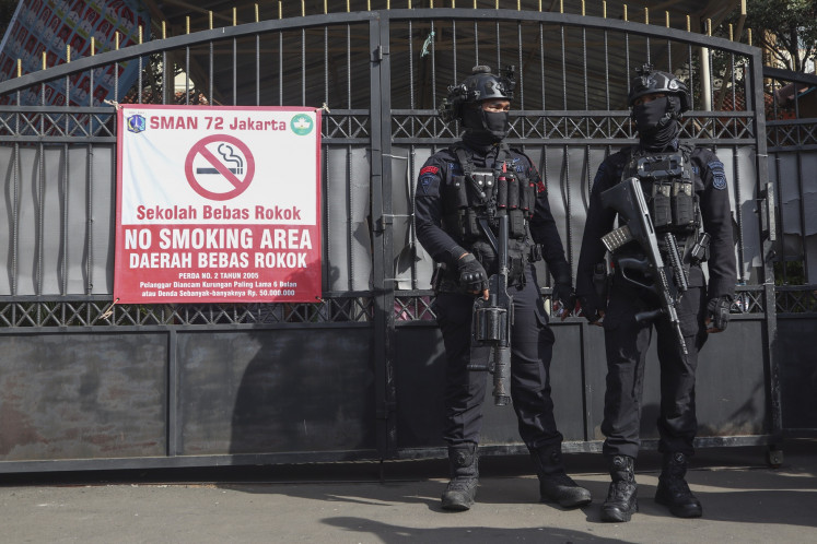 Two personnel of the Jakarta Police's Gegana (bomb squad) stand guard on Nov. 7 in front of the gate of SMAN 72 Jakarta state senior high school in Jakarta. Ninety-six people were injured in two blasts on Nov. 7 inside a mosque at the school complex.