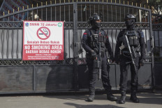 Two personnel of the Jakarta Police's Gegana (bomb squad) stand guard on Nov. 7 in front of the gate of SMAN 72 Jakarta state senior high school in Jakarta. Ninety-six people were injured in two blasts on Nov. 7 inside a mosque at the school complex.