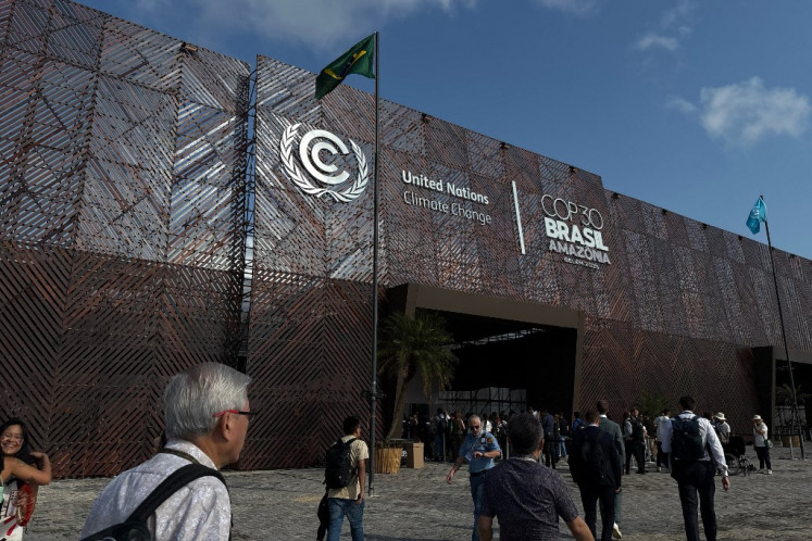Attendees walk in front of the main entrance to the United Nations climate change conference, or COP30, on Nov. 10 in Belém, Brazil. Participants of the COP30, running from Nov. 10 to 21, face the daunting task of keeping global climate cooperation from collapsing.