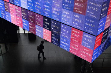 A man walks below an electronic quotation board displaying the Nikkei 225 stock prices on the Tokyo stock Exchange in Tokyo on Nov. 5, 2025.