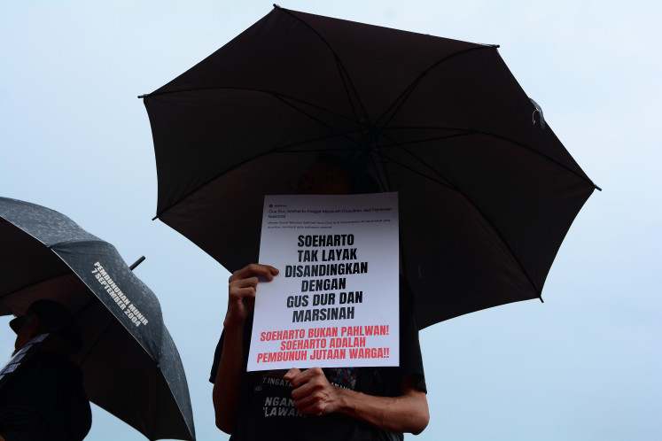 An activist holds a poster rejecting the proposal to name former president Soeharto a national hero during the Kamisan rally on Oct. 23, 2025, in front of the State Palace in Central Jakarta.
