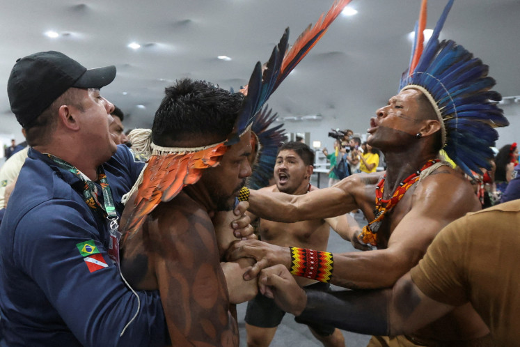 An indigenous demonstrator is held by a staff member on Nov. 11, 2025, as protesters force their way into the venue hosting the United Nations Climate Change Conference (COP30), in Belem, Brazil.