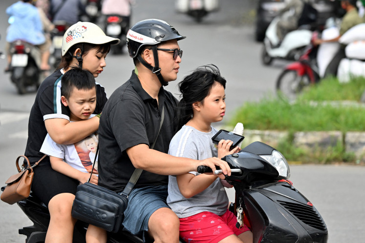 Loaded wheels: A family of four rides a motorcycle on June 4 on a road in Hanoi.