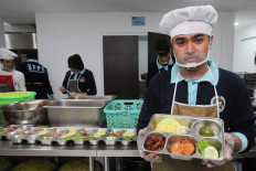 A worker at the Surabaya Police’s nutrition fulfillment service unit (SPPG) shows a tray of food to be distributed under the free nutritious meal program on Oct. 29, 2025, in the East Java capital. 