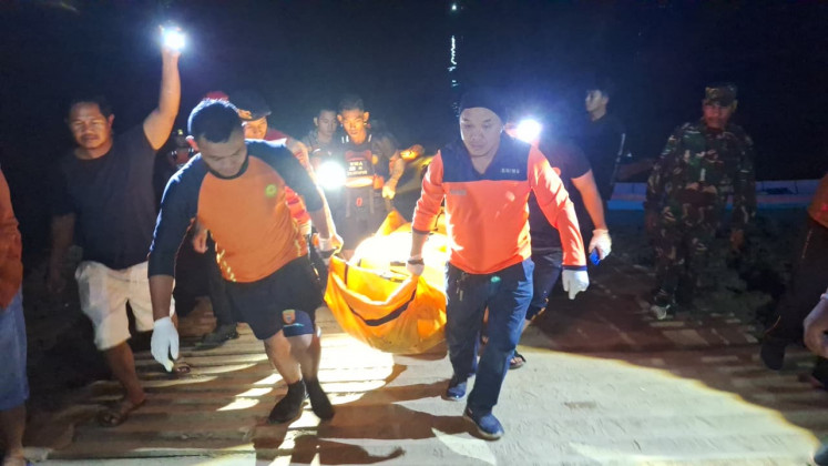 Rescue workers carry the body of Pendy, a passenger of a sunken Ferry, on Wednesday, after it was found some 10.7 kilometers from the accident site. The overloaded ferry sank on Monday evening amid a strong river current, killing eight passengers while 20 others were rescued.