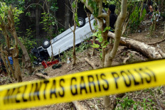 People look at the wreckage of a tourist bus one day after it plunged into a ravine in Uluwatu, Bali on November 19, 2013.