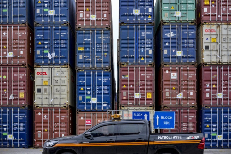 A vehicle rides past stacks of cargo containers on July 7 at the Jakarta International Container Terminal at the Tanjung Priok Port in North Jakarta