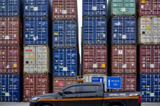 A vehicle rides past stacks of cargo containers on July 7 at the Jakarta International Container Terminal at the Tanjung Priok Port in North Jakarta