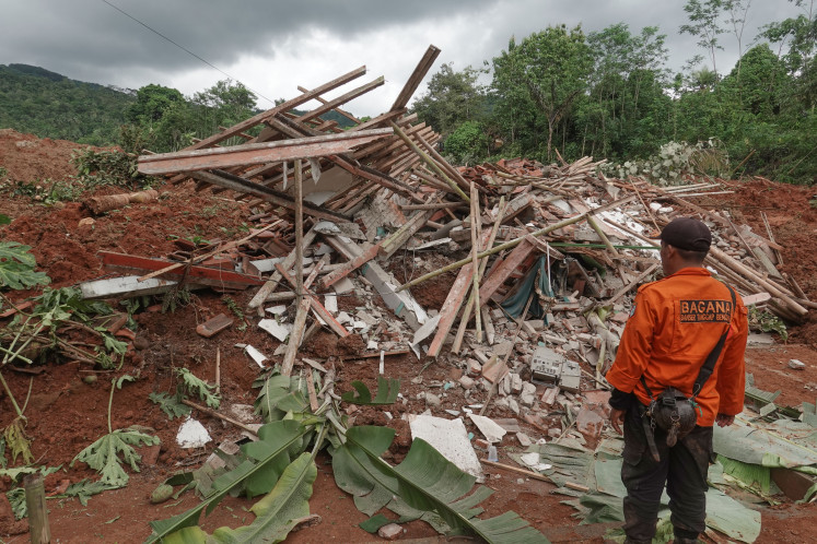 Rescue personnel stand in front of a destroyed home in Cibeunying village, Majenang district, Cilacap regency, Central Java, on Nov. 14, 2025. A landslide hit the village the previous day, burying 16 houses and leaving three people dead with 20 others still missing.