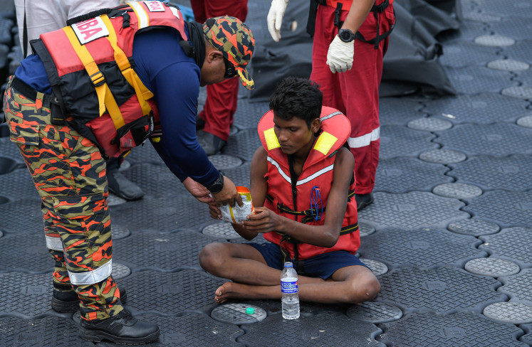 A Malaysian rescuer provides food to Rohingya migrant Iman Shorif (right), days after his boat carrying migrants from Myanmar capsized on Nov. 10 near the Malaysia-Thailand border, at a jetty in Langkawi, Malaysia. 