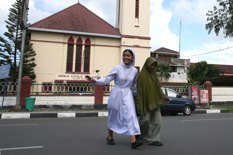 A Sacred Heart Catholic Church nun (left) helps a Muslim woman cross the street on Nov. 16, 2025, in Banda Aceh. UNESCO declared International Tolerance Day on Nov. 16, 1955, which has since been used to promote care and togetherness among people from different ethnicities and religions.