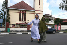 A Sacred Heart Catholic Church nun (left) helps a Muslim woman cross the street on Nov. 16, 2025, in Banda Aceh. UNESCO declared International Tolerance Day on Nov. 16, 1955, which has since been used to promote care and togetherness among people from different ethnicities and religions.