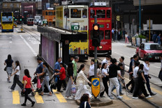 People cross a street in Western district of Hong Kong on July 15, 2025. 