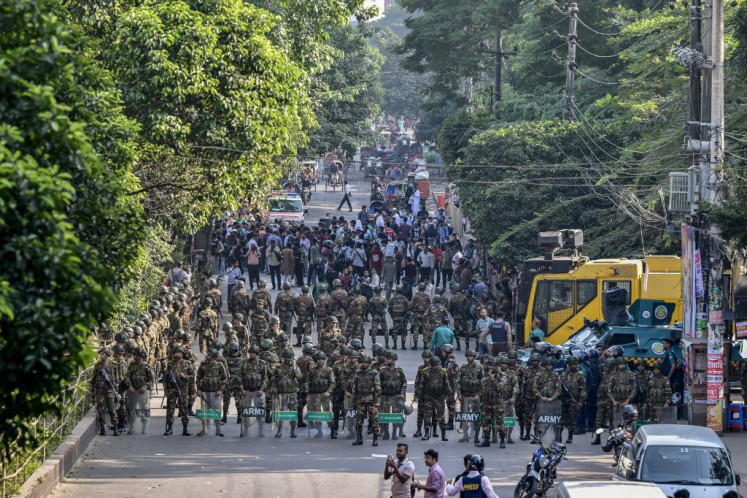 Security personnel stand guard on Nov. 17 as demonstrators attempt to demolish the residence of Sheikh Mujibur Rahman, Bangladesh's first president and father of the country's fugitive prime minister, Sheikh Hasina, in Dhaka. 