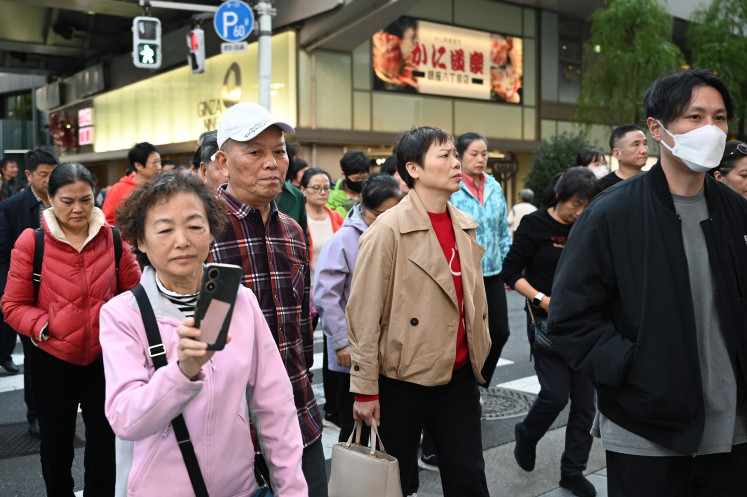 A spat affects tourism: Members of a Chinese tour group cross a road in the Ginza shopping district on Monday in Tokyo. Japanese tourism and retail shares dived on Monday, Nov. 17, after China warned its citizens to avoid the tourist hot spot in a spat over Prime Minister Sanae Takaichi’s comments on Taiwan.