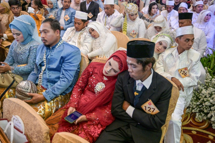 Brides and grooms take part in a mass officiating event on Aug. 27, 2025 organized by the Surabaya city administration for dozens of couples who previously wedded under local traditions, which are not legally recognized.