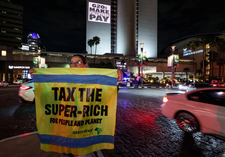 A Greenpeace activist holds a banner as she joins a Glasgow Actions Team projection in Johannesburg, South Africa, on Nov. 19, 2025, calling for bold debt reform, stronger climate action and urgent responses to the global development crisis as leaders prepare for the first G20 summit hosted in Africa.