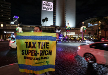 A Greenpeace activist holds a banner as she joins a Glasgow Actions Team projection in Johannesburg, South Africa, on Nov. 19, 2025, calling for bold debt reform, stronger climate action and urgent responses to the global development crisis as leaders prepare for the first G20 summit hosted in Africa.
