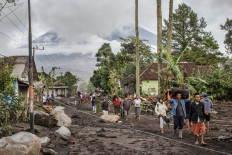 People walk on ground covered in volcanic ash after a pyroclastic flow during yesterday's eruption of Mount Semeru in Supiturang village, Lumajang, East Java on November 20, 2025. 
