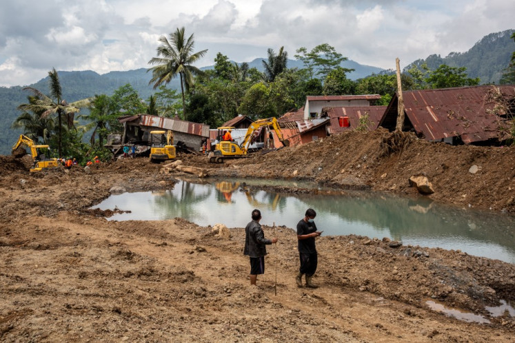 Residents walk at the site of a landslide in Situkung village, Banjarnegara, Central Java, on November 20, 2025.