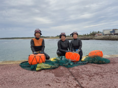 'Haenyeo', skilled female free divers, from Sagye-ri village in Jeju, South Korea, (from left) Lee Han-ok, 68, Kim Su-seon, 74, and Lee Bok-soo, 71, pose for a photo with the seafood they have brought back from their dives on Nov. 12, 2025.