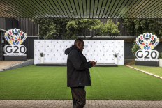 A delegate walks past Group of 20 (G20) logos displayed at the Nasrec Expo Centre in Johannesburg, South Africa on Nov. 21, 2025, ahead of the G20 Leaders' Summit.