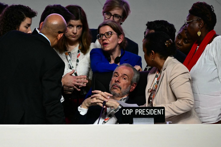 COP30 President Andre Correa do Lago (center) listens to his advisers next to United Nations Climate Change Executive Secretary Simon Stiell (left) after the plenary session was interrupted following Colombia's intervention at the COP30 UN Climate Change Conference in Belem, Para state, Brazil, on November 22, 2025. A proposed final deal for the UN climate talks omits any direct mention of phasing out fossil fuels, as demanded by the EU and many countries, according to the text published Saturday after two weeks of fraught negotiations.