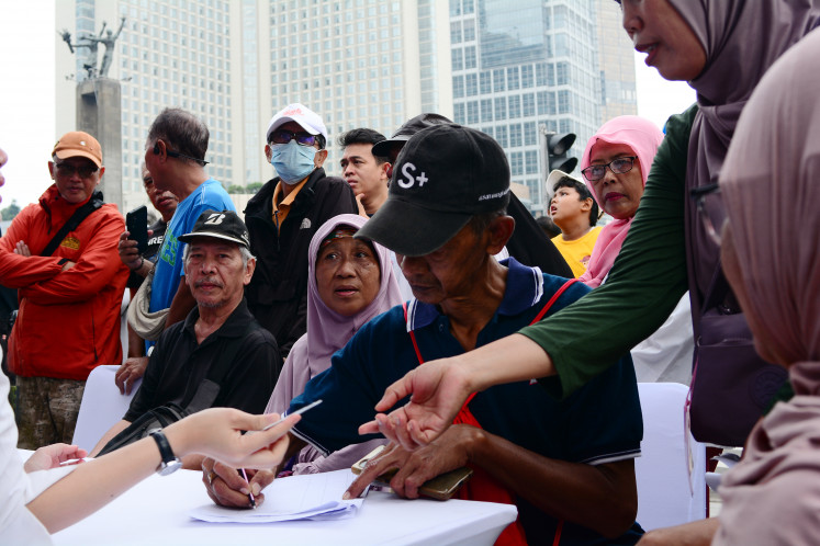 Elderly people fill out forms and wait in line on Nov. 23, 2025, to register or renew their Free Service Card (KLG) during Car Free Day at the Hotel Indonesia traffic circle in Central Jakarta. The event provides an opportunity for seniors aged 60 and above to obtain free access to public transportation services such as TransJakarta, MRT Jakarta and LRT Jakarta, offered by the Jakarta administration.